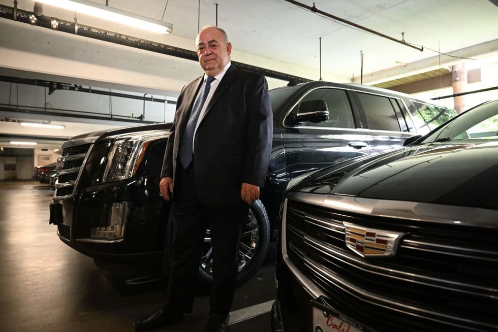 bald limo driver stands with cadillac cars in parking garage