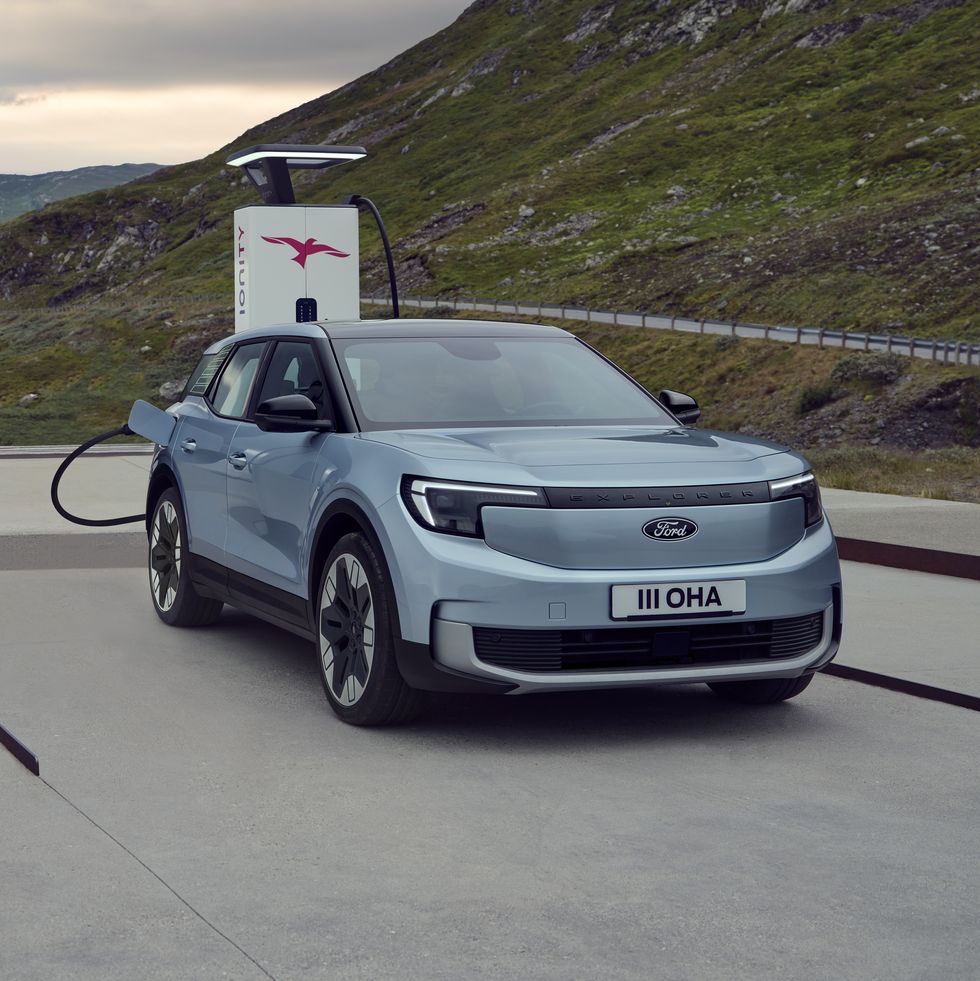 the ford explorer ev shown in light blue plugged in at a charging station