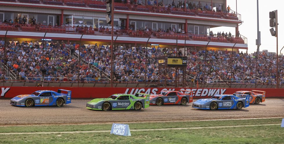 a group of race cars on a track with a crowd watching